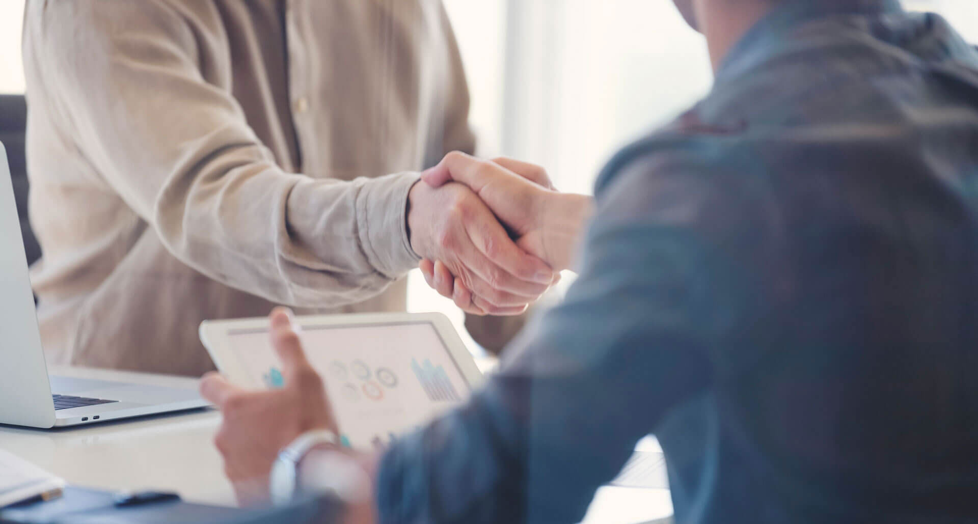 Zwei Personen geben sich nach Meeting einen Handschlag